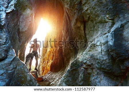 Young explorer standing in a cave with climbing equipment ready for action