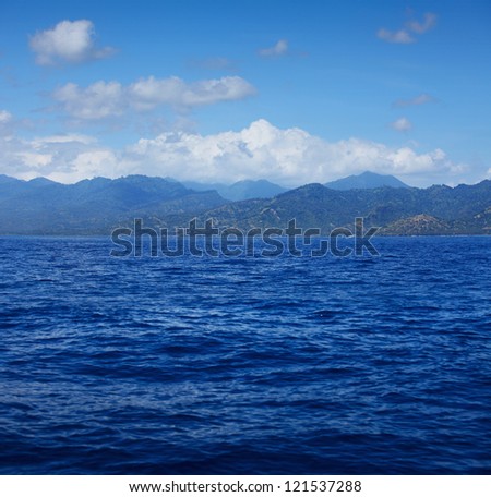 Blue tropical sea with waves and land with mountains ( Lombok island)