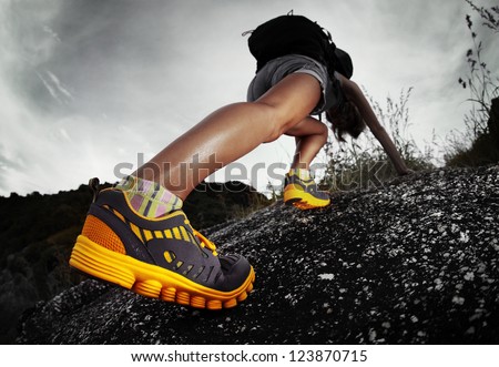 Hiker with backpack climbing rocky terrain. Focus on the boot