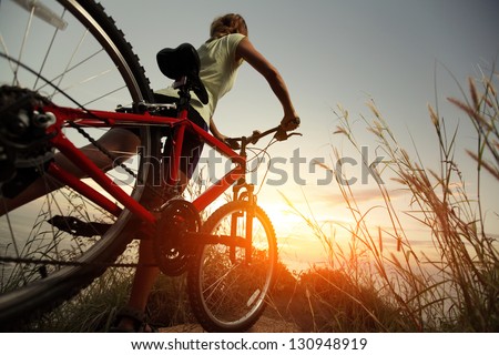 Young Lady With Bicycle On A Rural Road With Grass