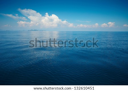 Tropical rippled and calm sea with far islands on the horizon and white fluffy clouds