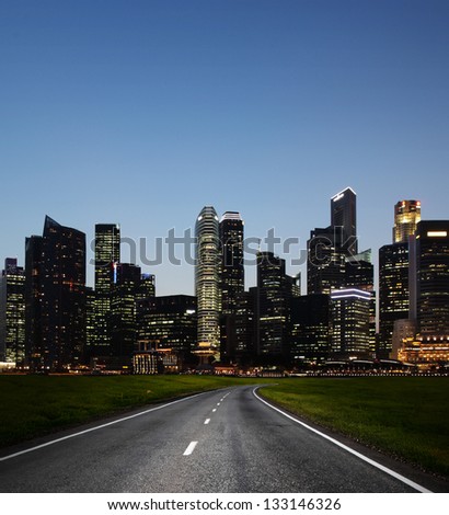 Asphalt road and a city with illuminated buildings on the horizon