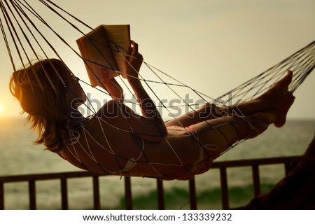Young Woman Reading A Book Lying In A Hammock On Tropical Resort