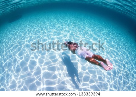 Young man diving on a breath hold in a tropical sea over sandy bottom