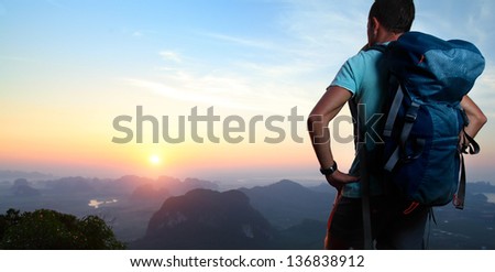 Hiker With Backpack Standing On Top Of A Mountain And Enjoying Sunrise.