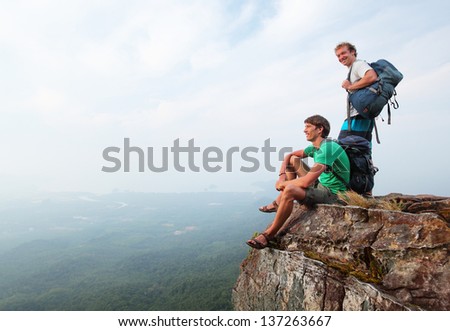 Two men standing on top of a mountain with backpacks