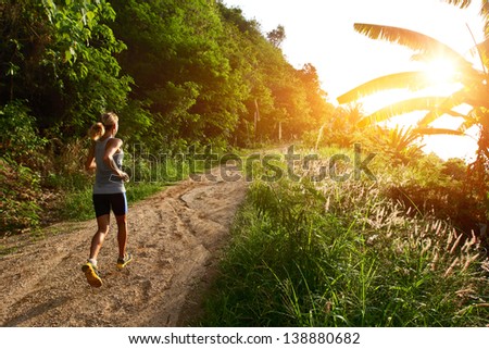 Young lady running on a rural road during sunset Young lady running on a rural road during sunset