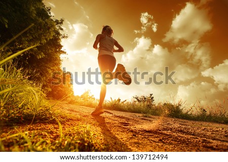 Young lady running on a rural road during sunset
