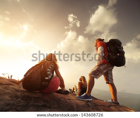 Group Of Hikers Relaxing On Top Of A Mountain And Enjoying Sunrise