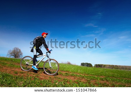 Young man cycling on a rural spring road at sunny day