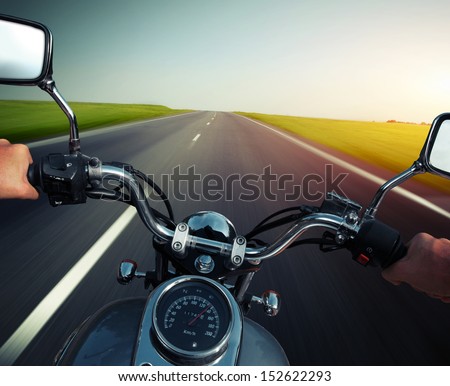 Driver riding motorcycle on an empty asphalt road