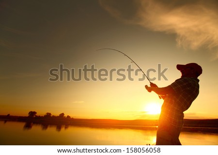Young man fishing from a boat at sunset