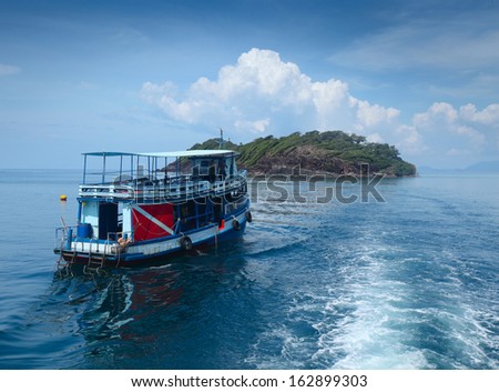 Dive boat heading to green island in a tropical sea. Thailand