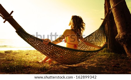Young Lady Relaxing In Hammock On The Tropical Beach At Sunset