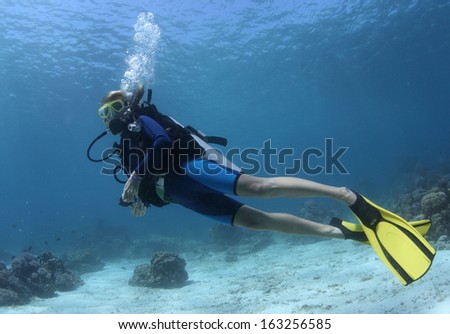 Diver swimming over sandy area in a tropical clear sea