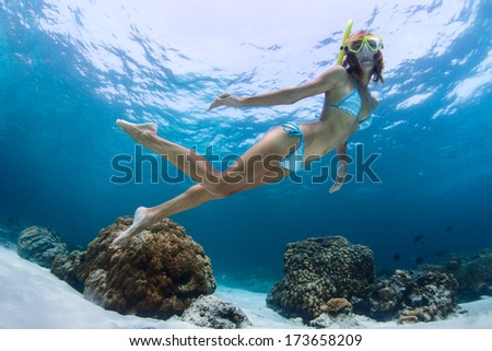Young lady swimming underwater over coral reefs in a tropical sea