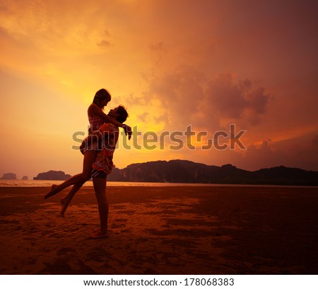 Young Couple Relaxing On A Tropical Beach At Sunset