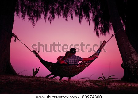Young couple enjoying tropical sunset in the hammock