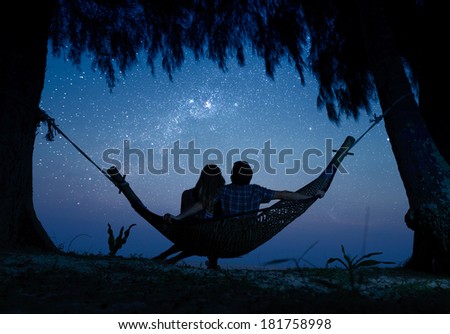 Couple relaxing in a hammock and enjoying starry sky