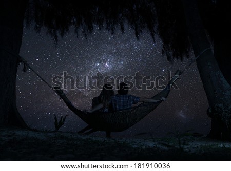 Couple relaxing in a hammock and enjoying starry sky