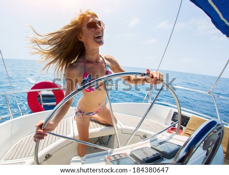 Young laughing woman steering the sail boat at sunny day