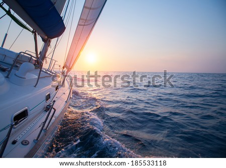 Sail boat in an open sea at sunset