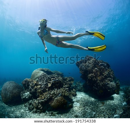 Young lady finning underwater over coral reef on a breath hold