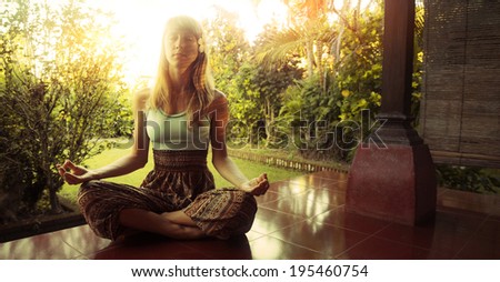 Young woman relaxing on the porch of house with green garden on the background