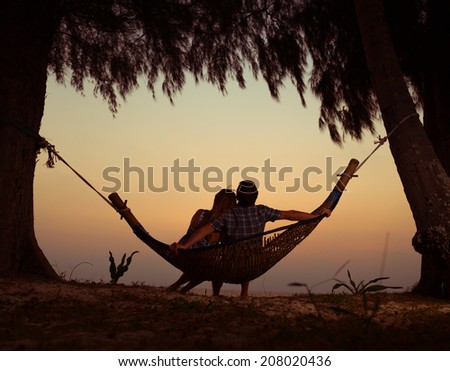 Young couple relaxing in the hammock at sunset