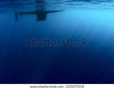 Underwater shot of two free divers ascending from a depth along the chain attached to the boat