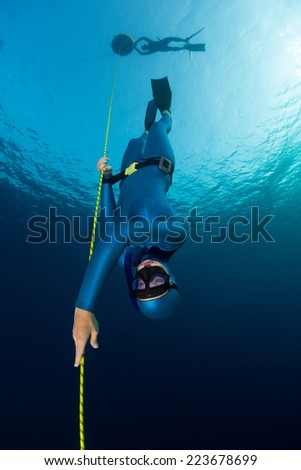 Lady free diver descending along the rope. Free immersion discipline