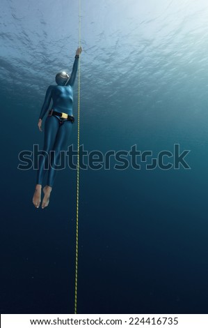 Lady free diver ascending along the rope. Free immersion discipline