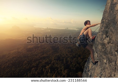 Young man climbing natural rocky wall at sunrise