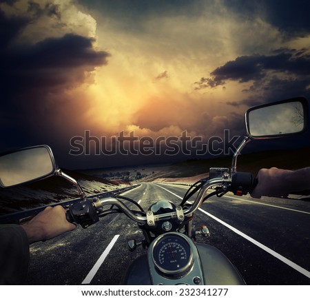 Rider on the motorcycle moving towards dark storm clouds