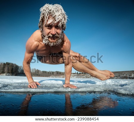 Man with frozen hair doing yoga exercise (parsva bakasana) on the ice