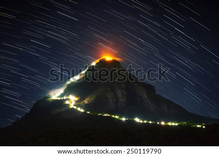 Mountain Adam\'s Peak (Sri Pada) illuminated at night with starry sky on the background. Sri Lanka