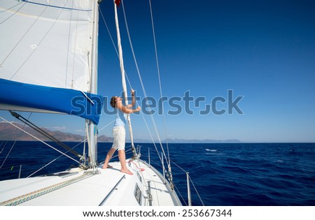 Young man standing on the yacht in the sea at sunny day