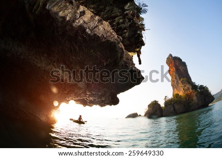 Young lady paddling the kayak in a bay with limestone mountains