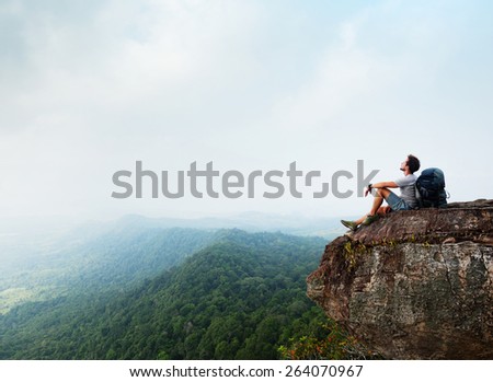 Hiker with backpack sitting on top of the mountain