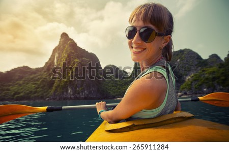 Smiling lady sitting in the kayak with limestone mountains of the Ha Long Bay (Vietnam) on the background.
