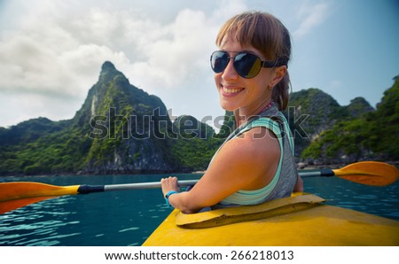 Smiling lady sitting in the kayak with limestone mountains of the Ha Long Bay (Vietnam) on the background.