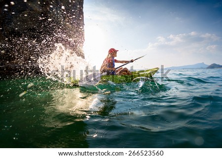 Young lady paddling hard the sea kayak with lots of splashes