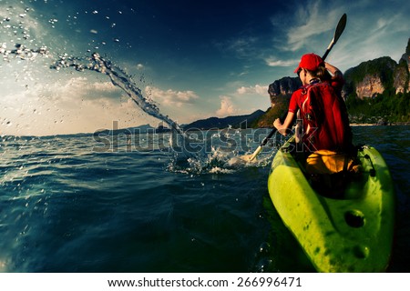 Young lady paddling hard the sea kayak with lots of splashes