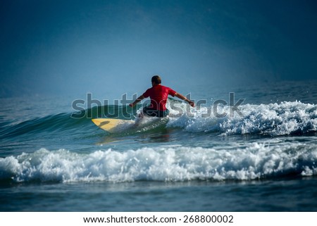 Surfer riding the wave on the short board at sunny day