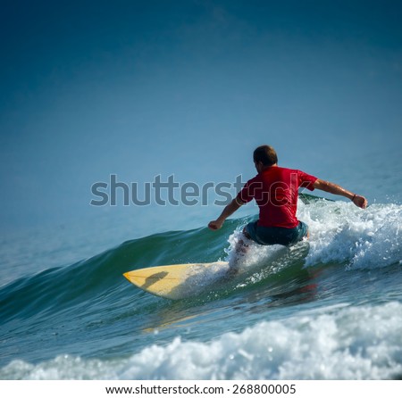 Surfer riding the wave on the short board at sunny day