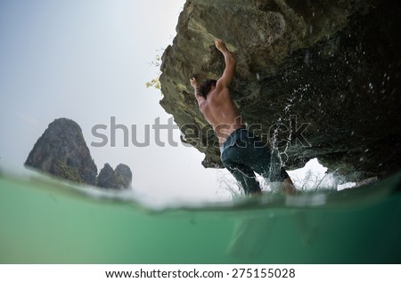 Young athlete trying to climb natural wall without belay. Deep water soloing.