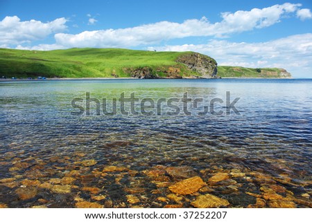 Blue sea with rocks land and blue sky with clouds