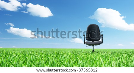 Office chair on a meadow with green grass and blue sky