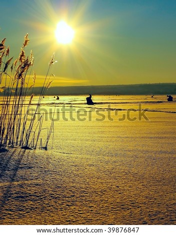Winter fishermens on ice under sun