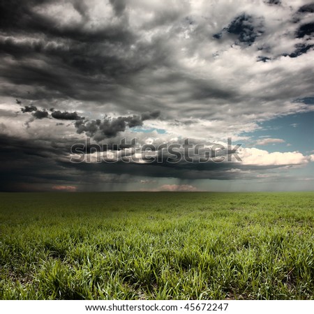 stock photo : Storm clouds with rain over meadow with green grass